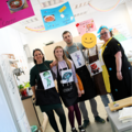 Gruppenbild: Fünf Schülerinnen und Schüler stehen zusammen im mit bunten Plakaten dekorierten Hauswirtschaftsraum in dem sie die Gäste bewirten werden.