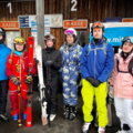 Gruppe von Schülerinnen und Schülern vor dem Kassenhäuschen in Mitterdorf. Sie tragen Skiausrüstung.