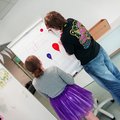 Personenbild: Ein Schüler und eine Schülerin stehen vor einem Flipchart, das sie mit bunten Ballons bemalen. Es trägt die Überschrift "Zirkus".